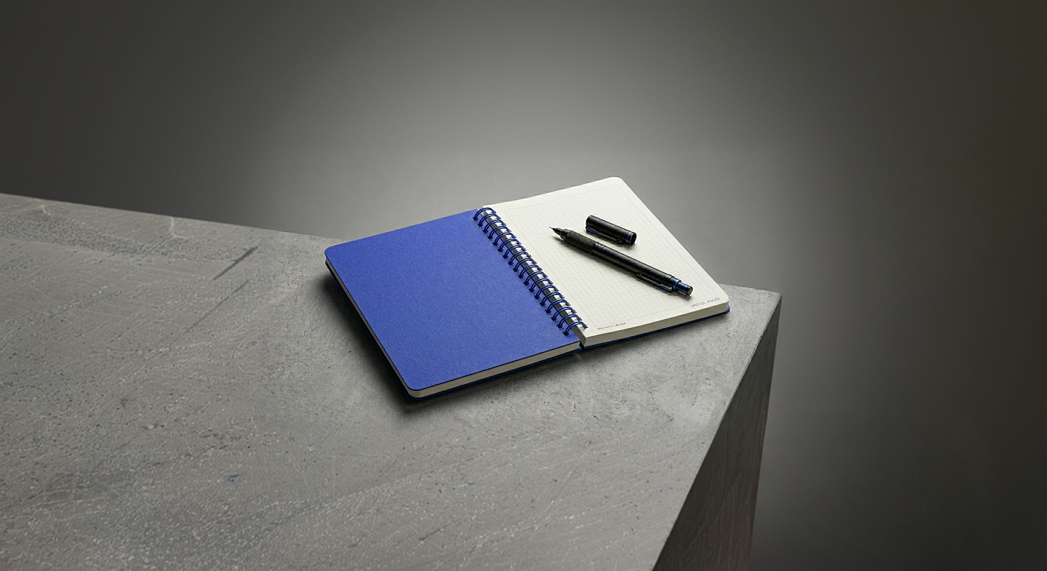 Editorial still life of a notebook on concrete, suggesting a clinical, diagnostic writing surface